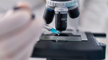 young-hispanic-man-wearing-scientist-uniform-using-microscope-laboratory